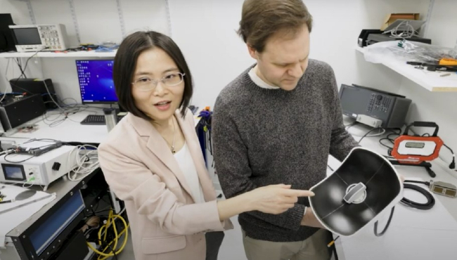 Dr. Zhen Xu, points to a small device and explains how it works.