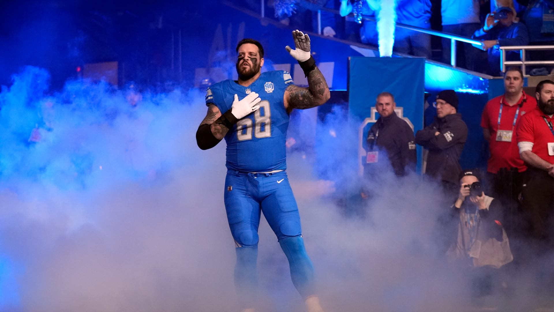 Taylor Decker acknowledges the fans as he runs out of the Ford Field tunnel amid blue lights and smoke.