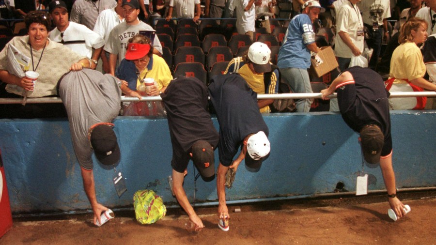 Fans use cups to gather dirt from Tiger Stadium following the ballpark’s final game on Sept. 27, 1999. (Jeff Kowalsky/Getty Images)