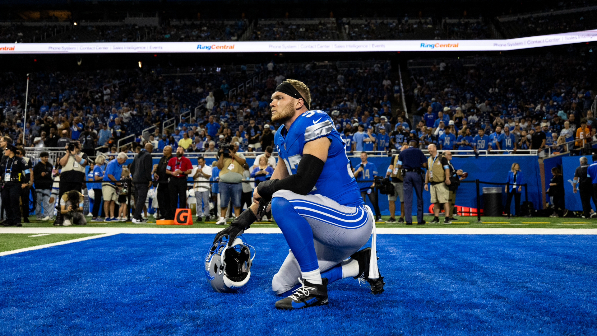 Aidan Hutchinson kneels in the end zone ahead of a game at Ford Field.