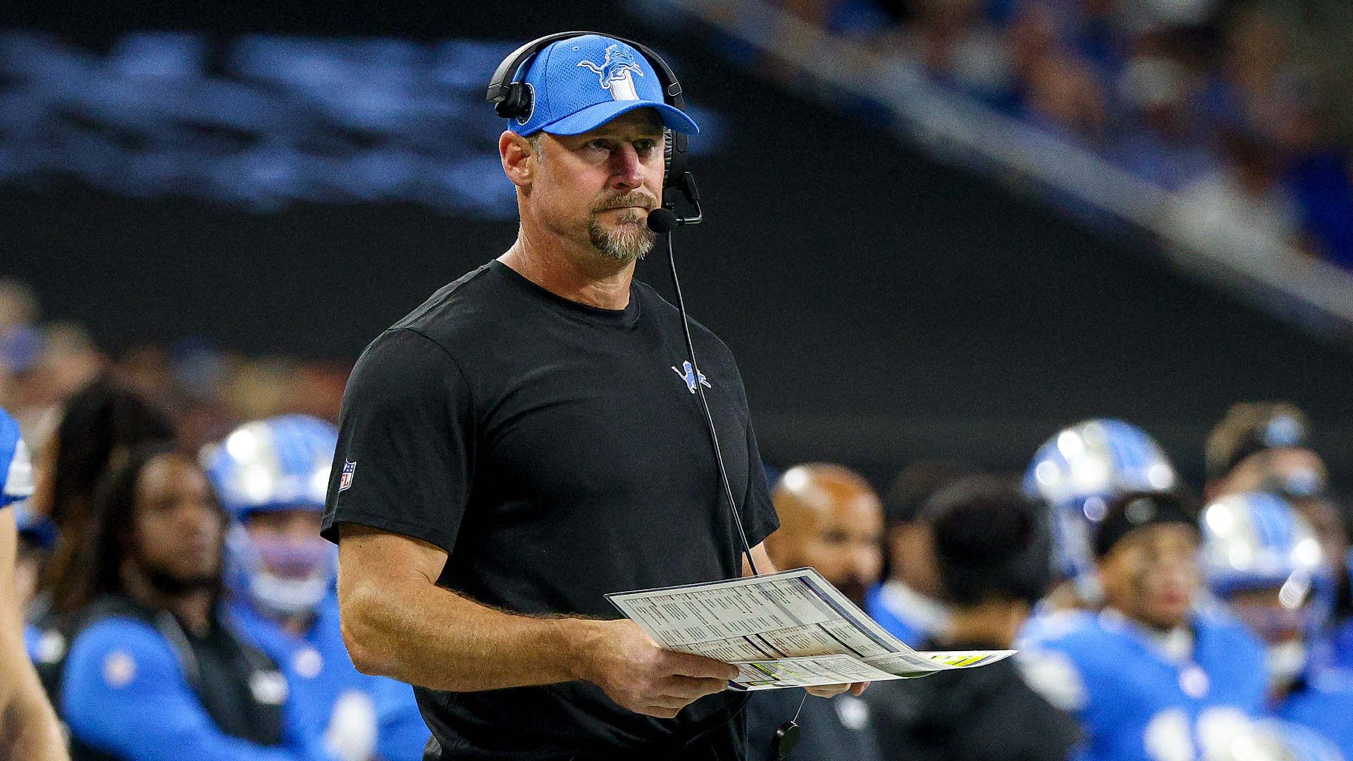 Dan Campbell looks on while holding his play sheet.
