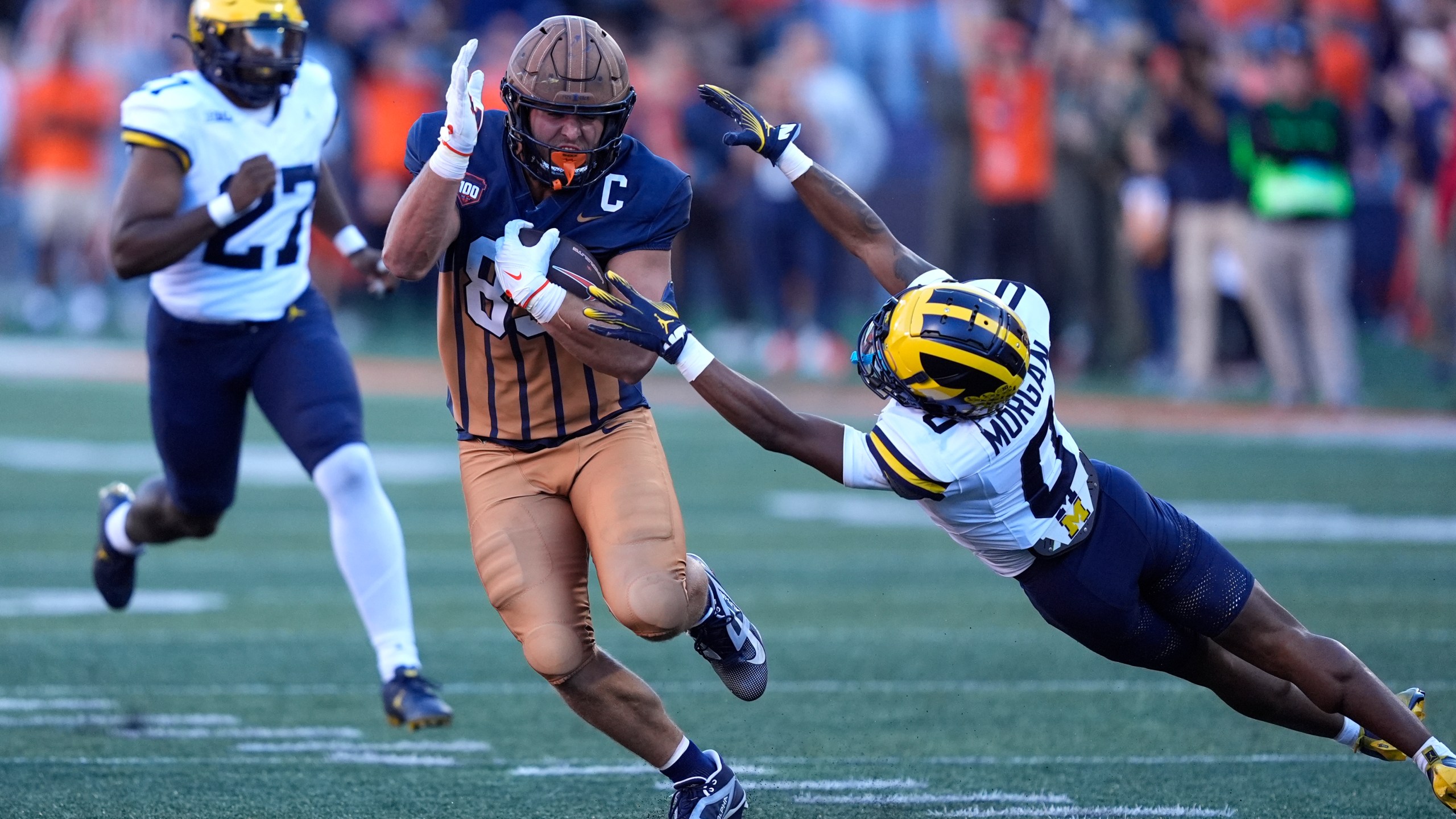 Illinois tight end Tanner Arkin sidesteps a tackle by Michigan's Semaj Morgan on a fake punt during the second half of an NCAA college football game Saturday, Oct. 19, 2024, in Champaign, Ill. (AP Photo/Charles Rex Arbogast)