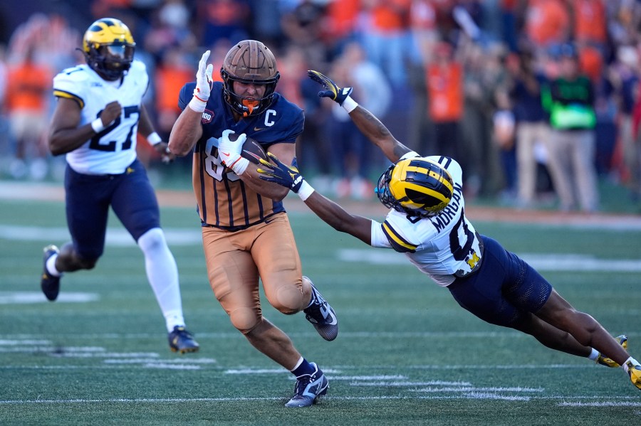 Illinois tight end Tanner Arkin sidesteps a tackle by Michigan's Semaj Morgan on a fake punt during the second half of an NCAA college football game Saturday, Oct. 19, 2024, in Champaign, Ill. (AP Photo/Charles Rex Arbogast)