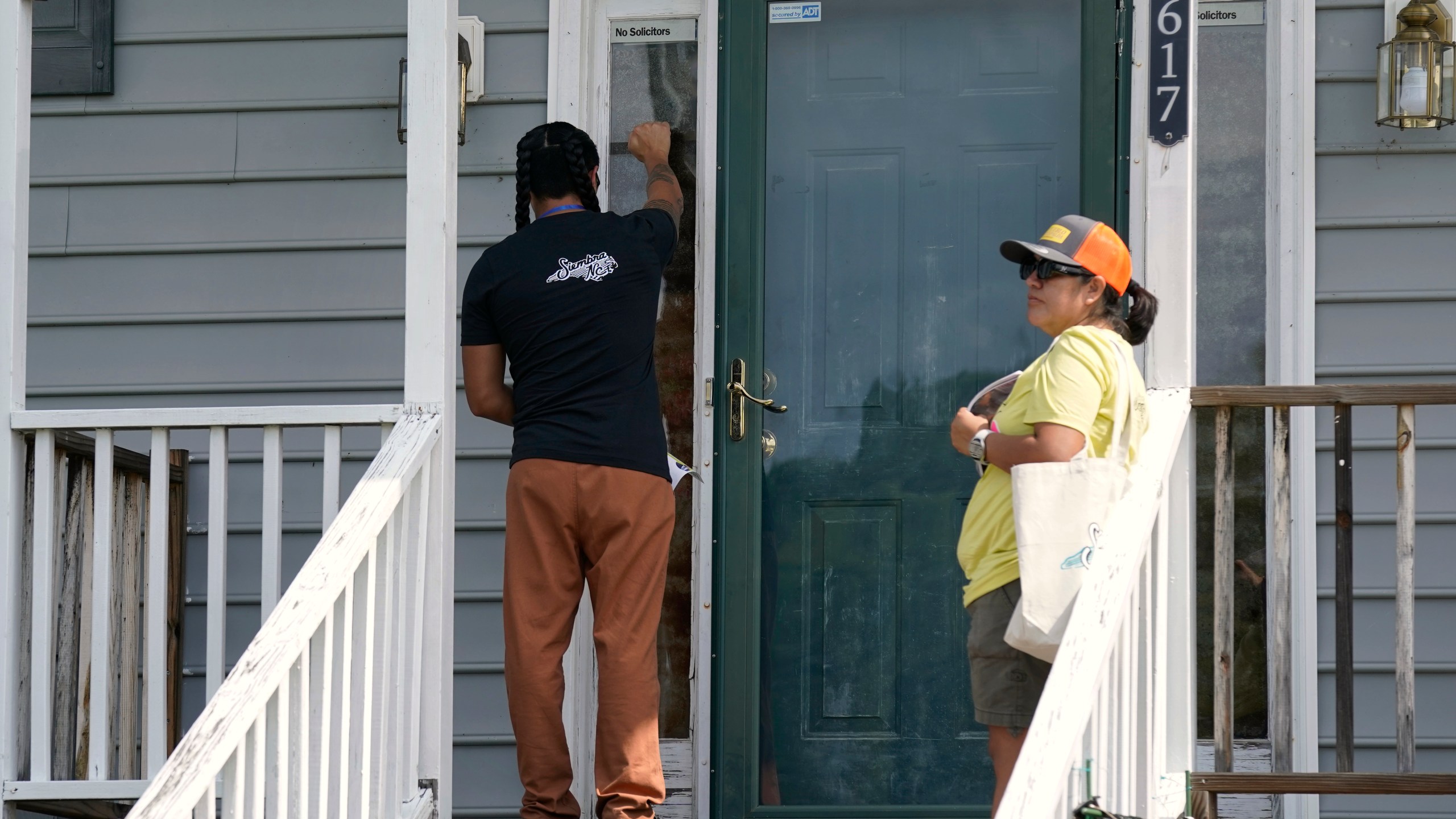 Salvador Fonseca, left, and Elena Jimenez knock on the door of a home during a voter engagement event for the Latino community in Greensboro, N.C., Saturday, Sept. 21, 2024. (AP Photo/Chuck Burton)