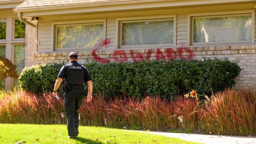 A West Bloomfield, Mich., police officer walks past vandalism spray painted on the home of University of Michigan president Santa Ono, Monday, Oct. 7, 2024, in West Bloomfield. (David Guralnick/Detroit News via AP)
