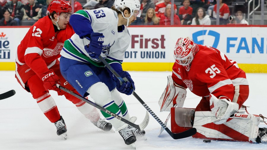 Detroit Red Wings goaltender Ville Husso (35) stop a shot-attempt by Vancouver Canucks center Teddy Blueger (53) with Red Wings center Marco Kasper, left, helping defend during the second period of an NHL hockey game Sunday, Dec. 1, 2024, in Detroit. (AP Photo/Duane Burleson)